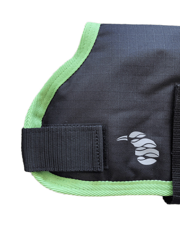 Close-up of the AniMac Lamb Coat | Waterproof in black with green trim, a sewn-on strap, and a white abstract curled logo on the right side.
