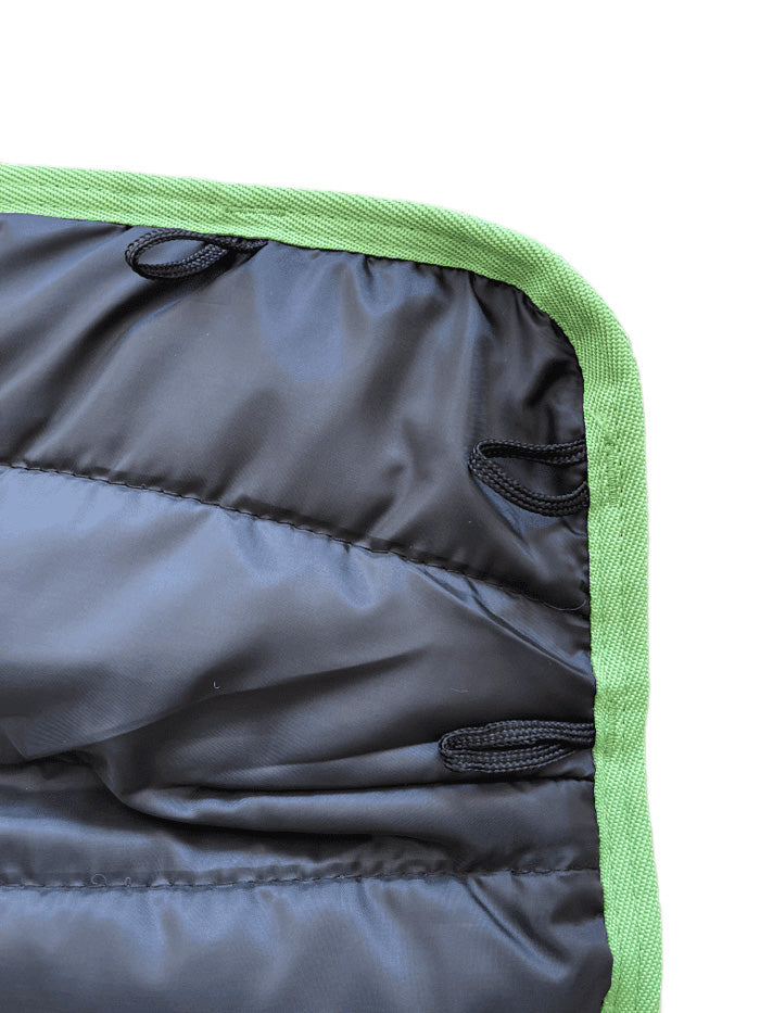 A close-up of the AniMac Lamb Coat | Waterproof shows its black quilted fabric with a green border and black fabric loops sewn along the edge.