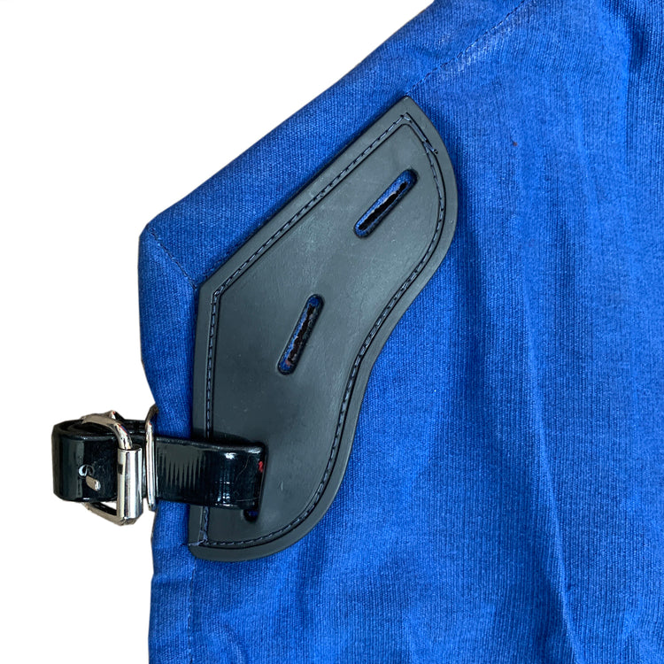 Close-up of AniMac's Canvas Turnout Rug | New Zealand 18oz Wool Lined Rug, showing blue canvas-like fabric, a black leather strap with buckle, stitched edging, and two horizontal slits in the leather accent piece.