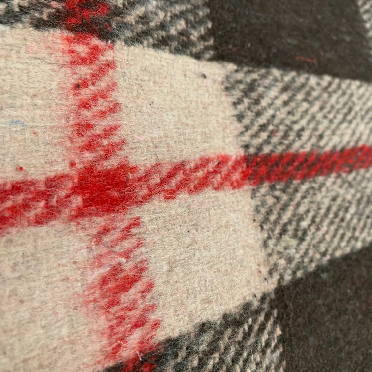 Close-up of AniMac’s Canvas Turnout Rug | New Zealand 18oz Wool Lined Rug showing its plaid design with intersecting red, black, and white checks on a cream background. The premium wool texture is clearly visible.