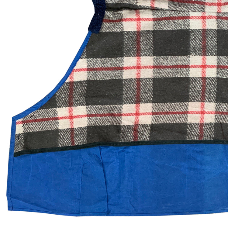 A close-up of the AniMac Canvas Turnout Rug | New Zealand 18oz Wool Lined Rug shows a plaid upper in black, white, gray, and red, with a solid blue pleated section below, reminiscent of classic horse rug designs.